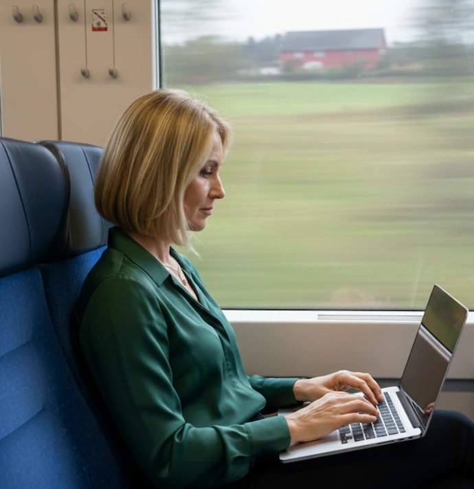 A woman is sitting in front of her laptop, studying on the train